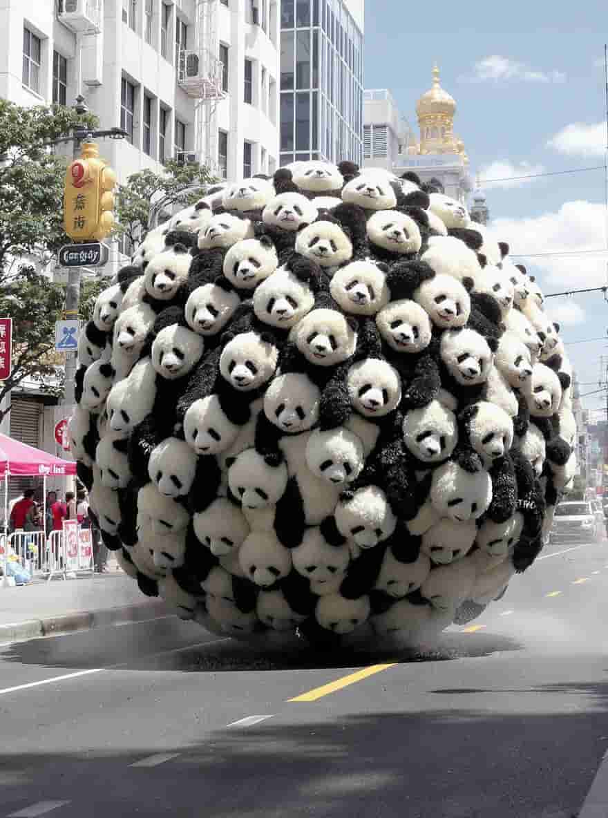Flux.1 Kontext generated image: A giant ball made of fluffy pandas rolling through the street...